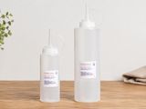 deux bouteilles de liquide posées sur une table, à côté d'une plante en pot