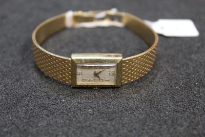 a gold bracelet with a watch on it on a table