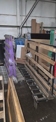 Dans un entrepôt, des cartons et des palettes sont empilés sur un tapis roulant