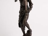 statue en bronze d'un garçon tenant un oiseau, posée sur un socle