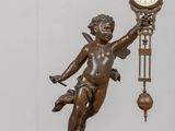 une statue représentant un garçon tenant une horloge posée sur une table