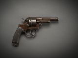 un vieux revolver posé sur une surface grise, sur fond noir