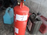 un extincteur rouge posé à côté de deux bidons bleus et d'un bidon rouge