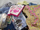 a pile of clothing and a book on a bed