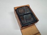 une boîte en bois sur laquelle est posée une horloge, posée sur une surface blanche