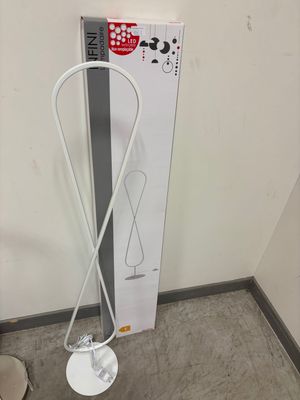 des toilettes situées dans un coin d'une pièce, équipées d'une brosse de toilettes et d'un distributeur de papier toilette