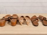 four pairs of sandals are lined up on a wooden table