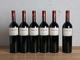 six bouteilles de vin rouge sont alignées sur une table en bois