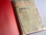 un livre ouvert, à la couverture rouge, posé sur une table