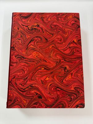 a red and black book sitting on top of a white table