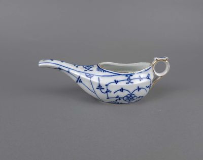 une vieille théière en porcelaine bleue et blanche, dotée d'une anse sur un fond gris