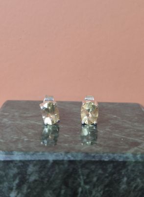 une paire de boucles d'oreilles à clous en diamant jaune posée sur un bloc de marbre