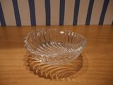 a glass bowl sitting on a table with a striped wall behind it