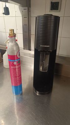 une bouteille d'eau posée à côté d'un distributeur d'eau sur le plan de travail de la cuisine