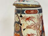 a vase with a lid that has a picture of a bird on it