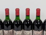 six bottles of red wine lined up in a row on a table