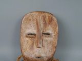 a wooden mask with a rope around it on a gray surface