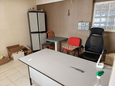 une pièce équipée d'une table, d'une chaise, d'un réfrigérateur et d'une fenêtre