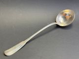 cuillère en argent avec un manche, posée sur une surface grise