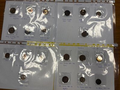 Plusieurs pièces de 25 centimes sont posées sur un morceau de papier, sur une table