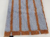 un gros plan d'un tapis bleu et orange posé sur une surface blanche