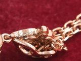 a close up of a gold plated necklace on a red velvet surface