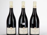 trois bouteilles de vin rouge sont alignées sur une table