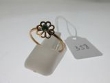une image représentant une bague en or ornée d'une fleur verte