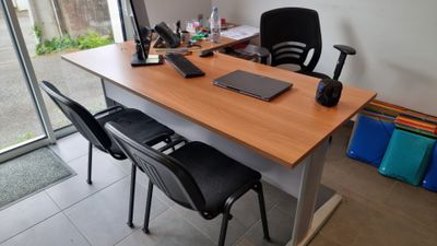 un bureau avec un ordinateur portable et deux chaises devant une fenêtre