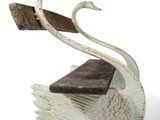 a white swan statue with a wooden seat on it
