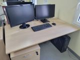 two computer monitors sitting on top of a wooden desk