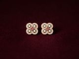 a pair of diamond and gold earrings on a maroon background