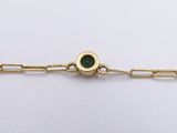 a close up of a gold chain bracelet with a green stone