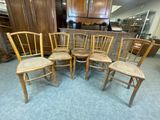 Six chaises en bois sont disposées en cercle dans une pièce.