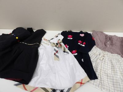 une pile de vêtements de bébé posée sur un lit recouvert d'une couverture
