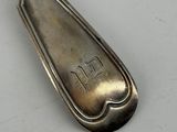 silver spoon with the word tlt on it sitting on a white surface