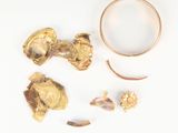 une photo d'une bague en or et d'autres objets posés sur un fond blanc
