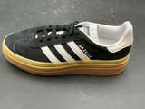 black and white adidas sneakers with gum soles on a gray surface