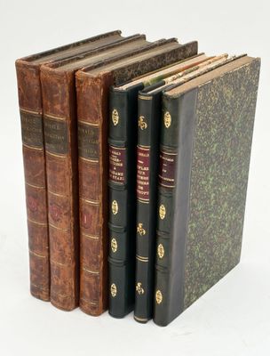 several old books are stacked on top of each other on a white surface