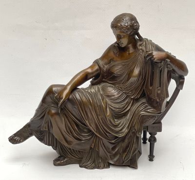bronze statue of a woman sitting on a chair with a dog