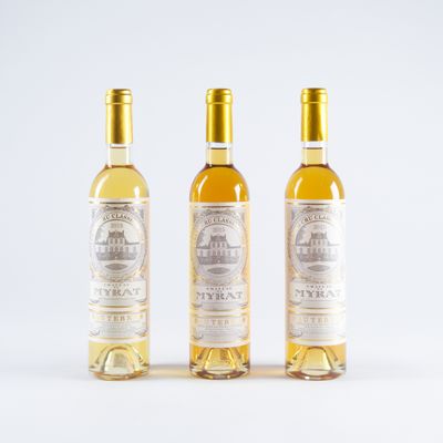 trois bouteilles de vin blanc posées l'une à côté de l'autre sur une surface blanche