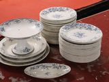 Plusieurs assiettes et bols sont empilés sur une table recouverte d'une nappe rouge.