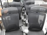 Plusieurs chaises de bureau noires sont alignées en rang dans une pièce