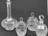 three clear glass vases and a decanter on a black background