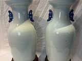 two white vases with blue handles sitting on a table