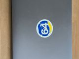 silver laptop with blue and yellow sticker sitting on a wooden surface