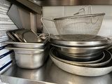 many pots and pans sitting on a shelf in a kitchen