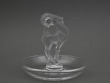 a glass ram figurine sitting on a glass plate