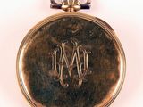 a gold pocket watch with a monogram on it