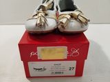 pair of white and gold shoes on a red box on a white surface